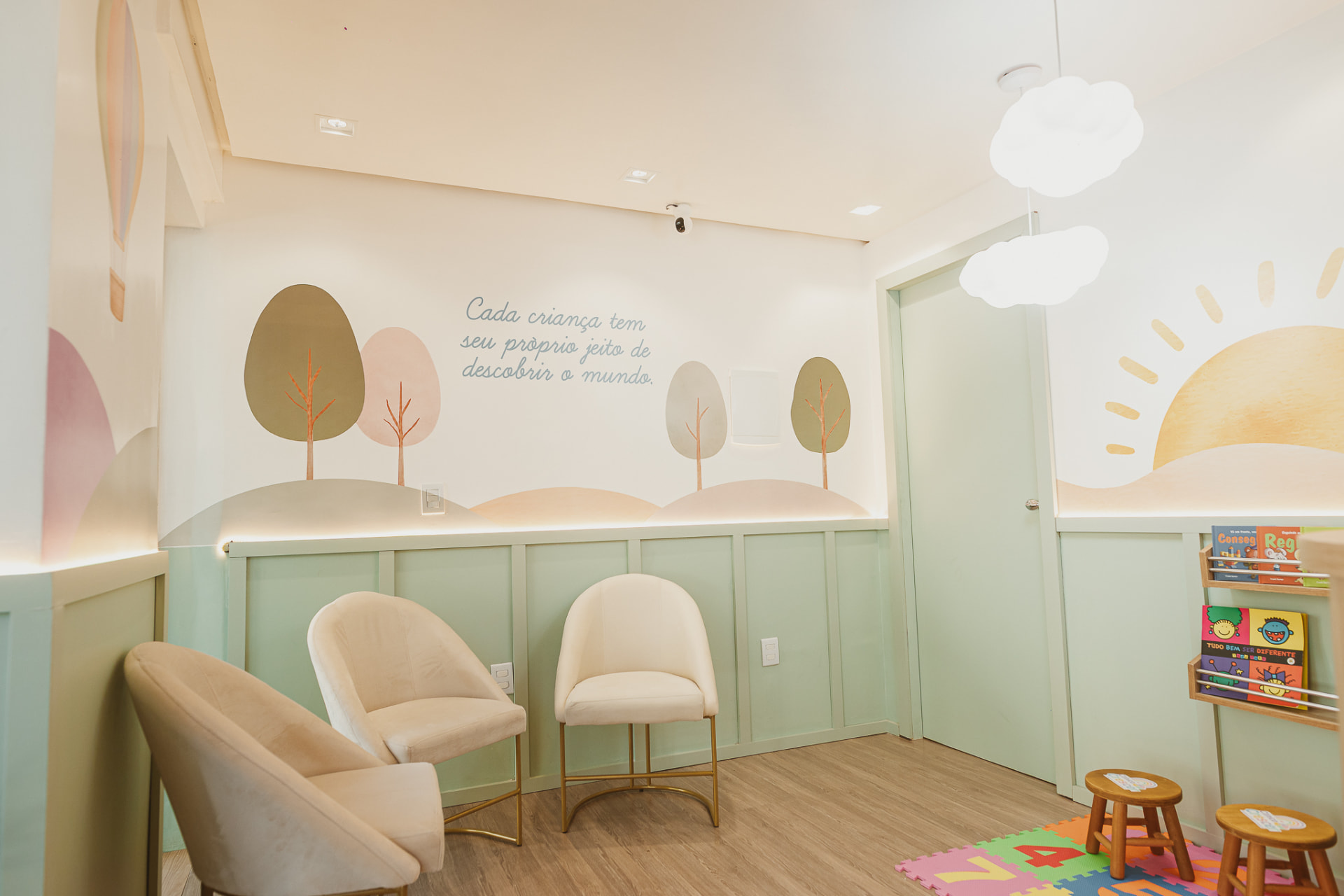 Sala de espera com poltronas claras e mural de árvores em tons pastel