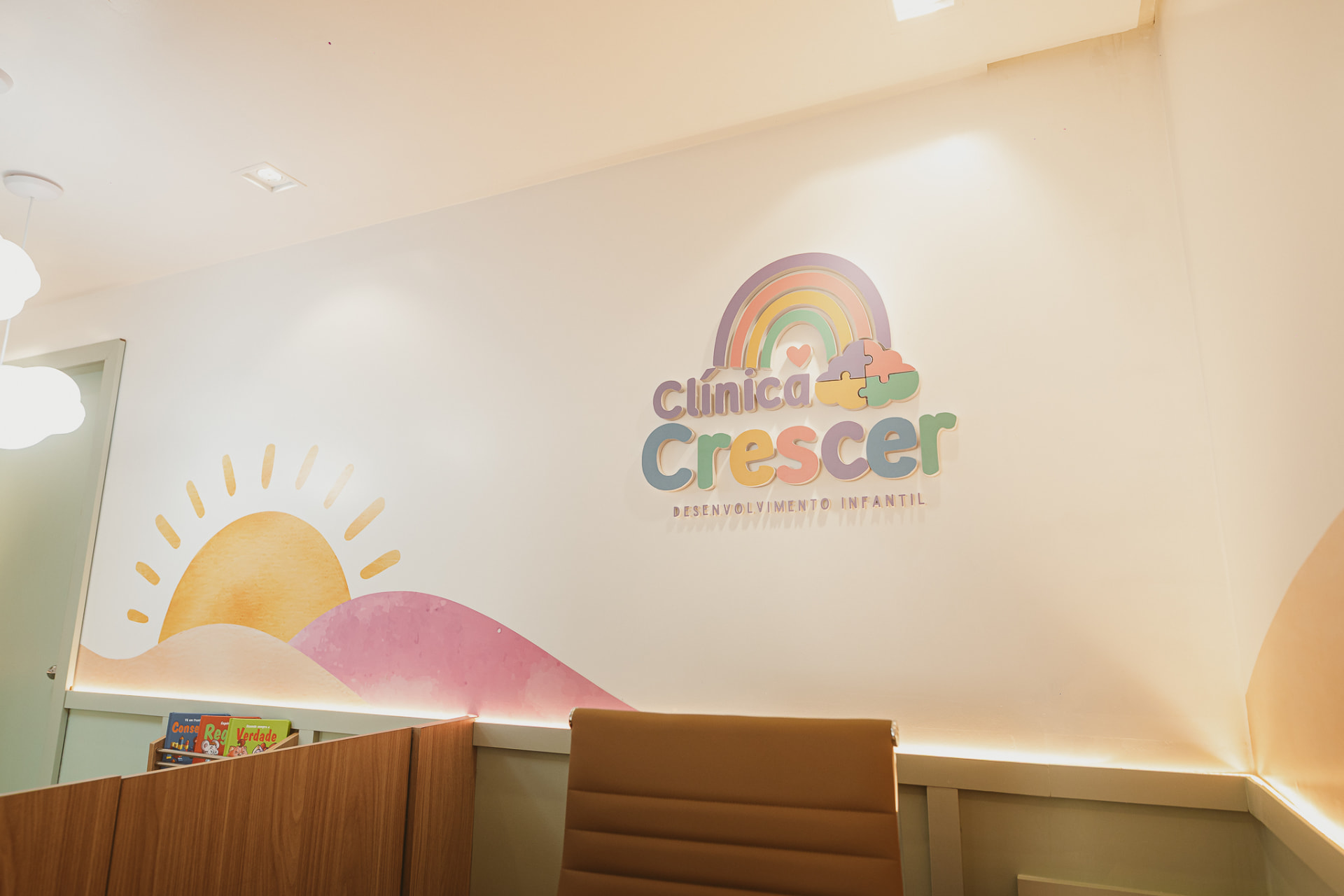 Parede da recepção com o logotipo da Clínica Crescer e mural do sol