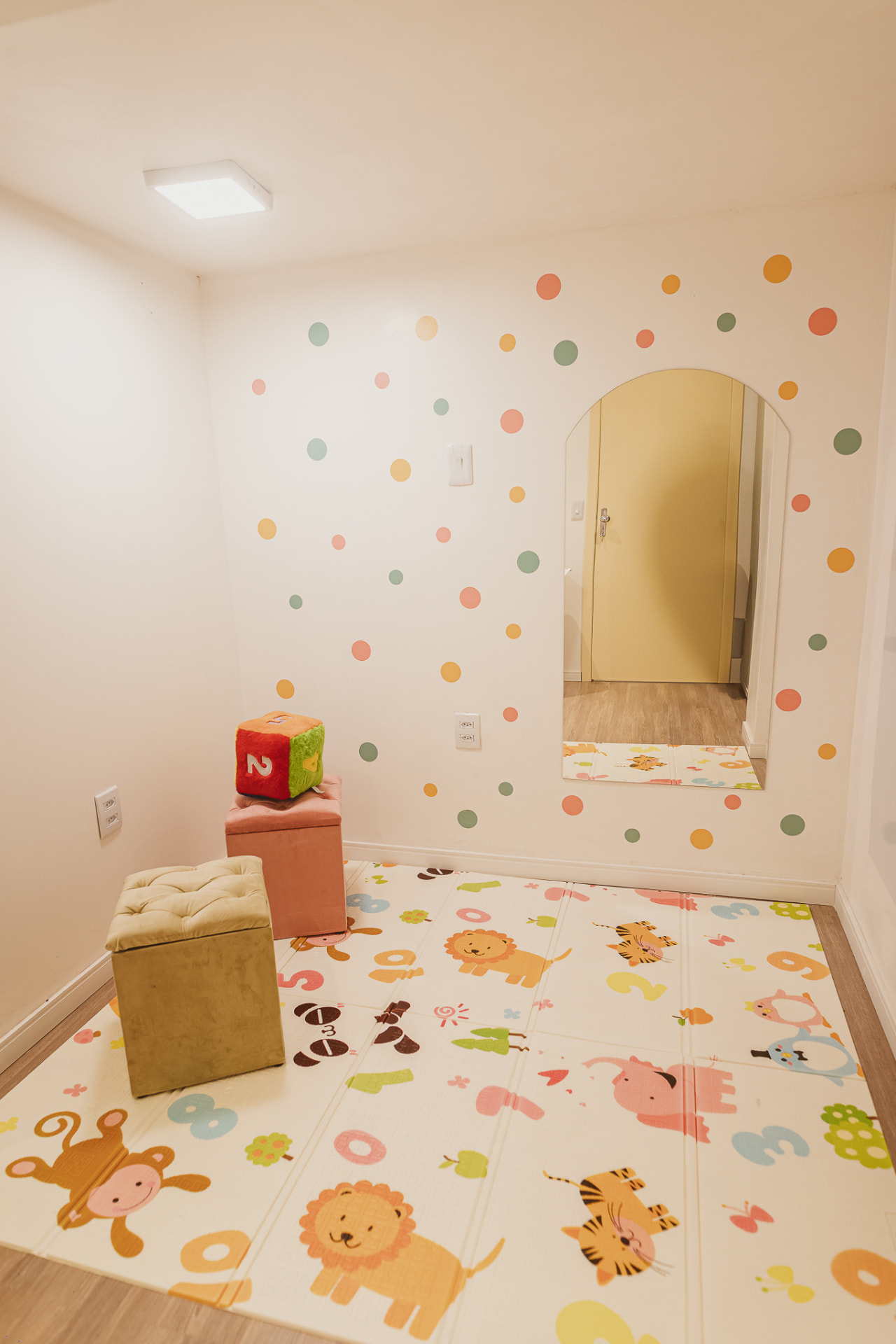 Sala lúdica com tapete de atividades, espelho e pufes